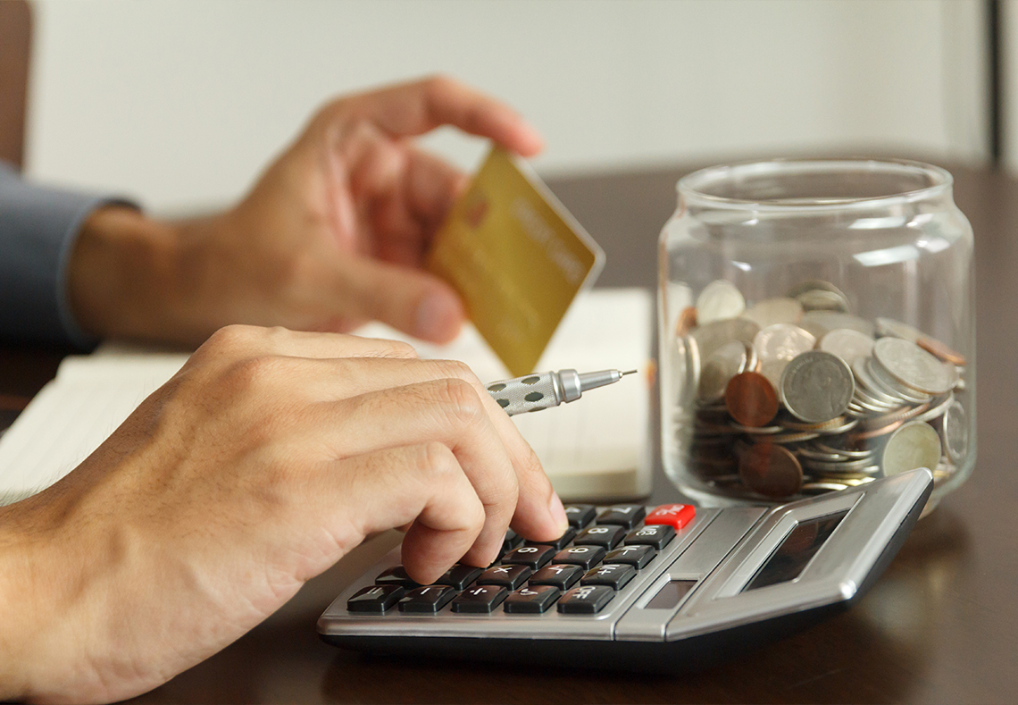 En person hanterar sina skulder vid en miniräknare