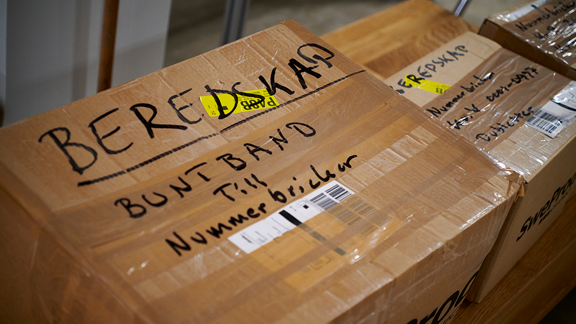 Kartonger märkta med handskriven text, däribland "BEREDSKAP" och fraktsedlar.