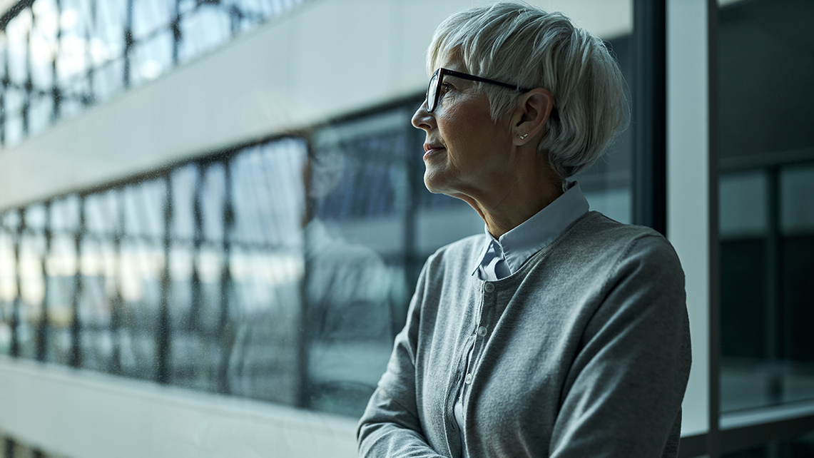 Äldre person på ett kontor som ser ut genom ett fönster för att illustrera artikeln om åldersdiskriminering