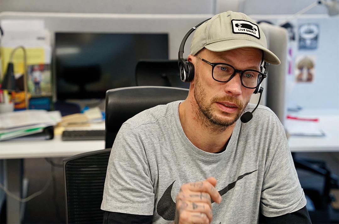 Jonas Söderlund i keps och headset tar emot ett telefonsamtal på Bris kontor.
