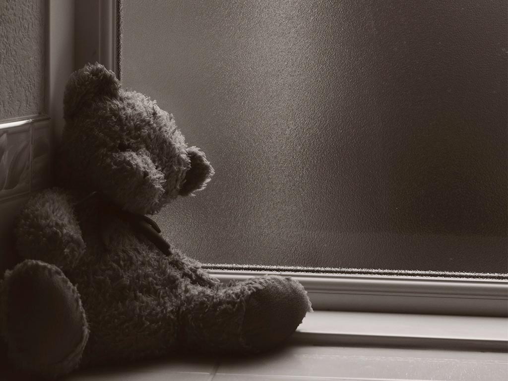 En ensam teddybjörn sitter i ett hörn.