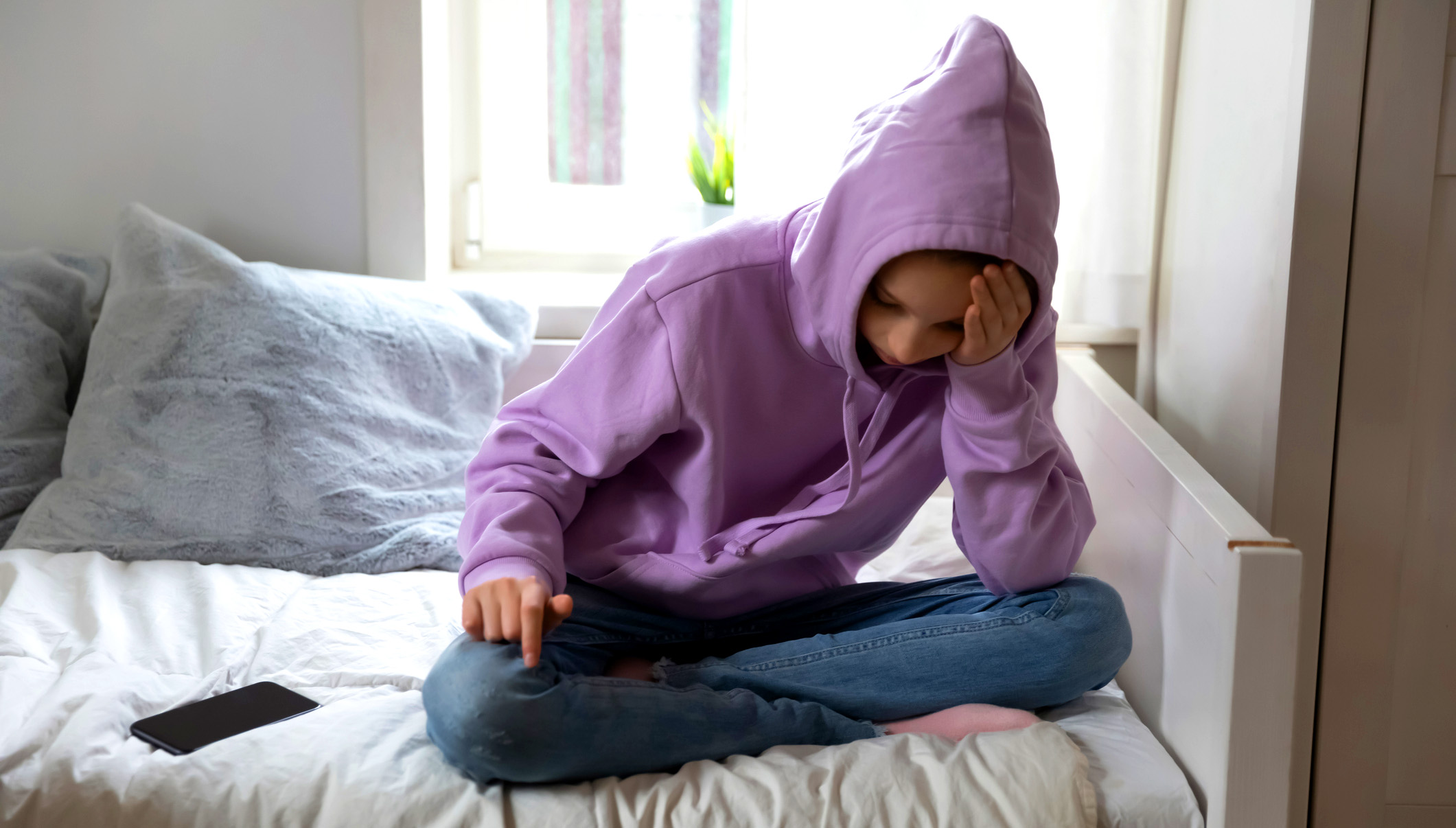 Sad depressed teen girl sit on bed at home suffer from lack of friends communication, unhappy depressed introvert teenager feel outcast lonely, have mental psychological problems, puberty concept