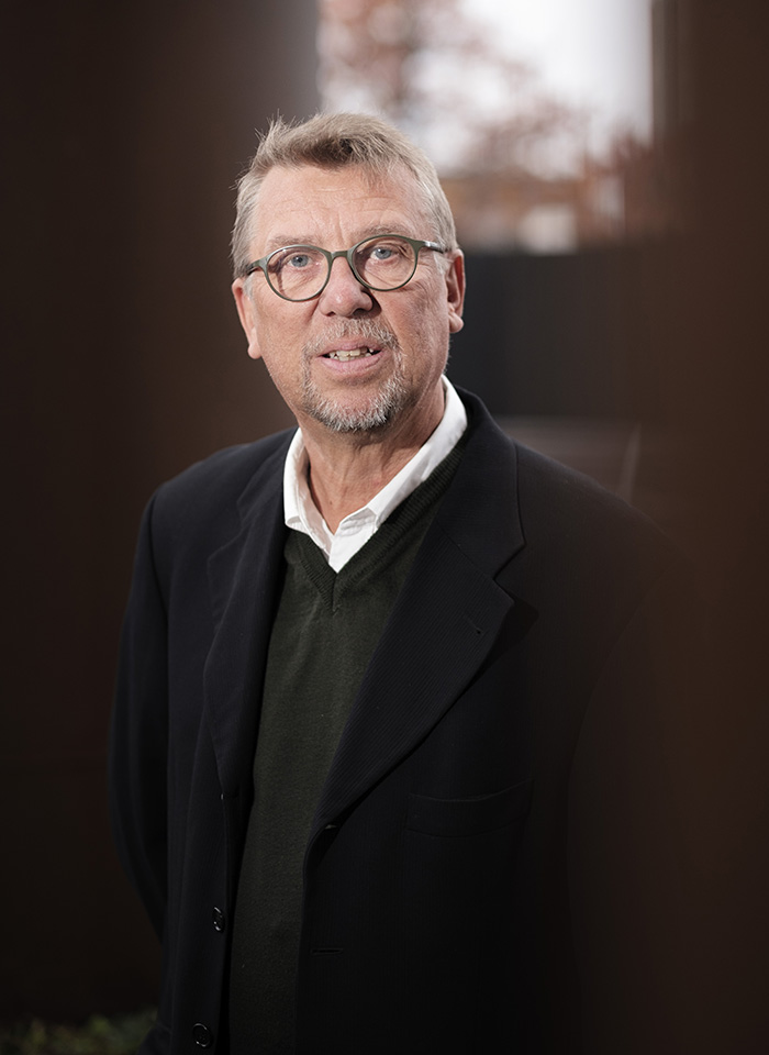 Porträttbild på Tapio Salonen, professor i socialt arbete vid Malmö universitet, i halvprofil framför mörkbrun bakgrund