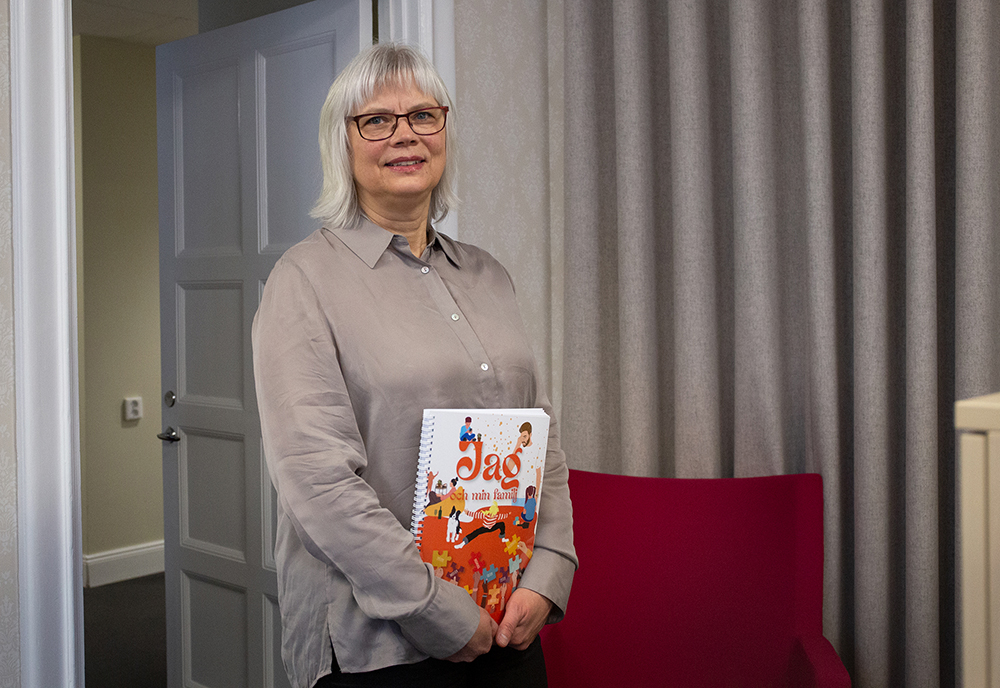 En kvinna som heter Ann Lyrberg porträtteras i halvfigur hållandes i ett häfte om metoden Jag & min familj.
