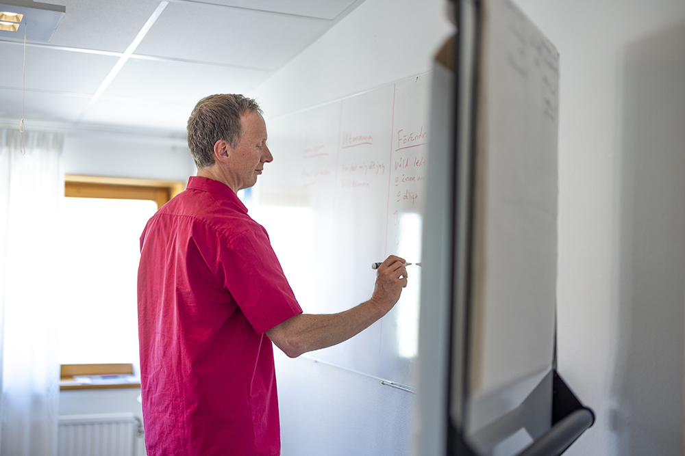 Frivårdsinspektören Mats Ädel står och skriver på en whiteboard.