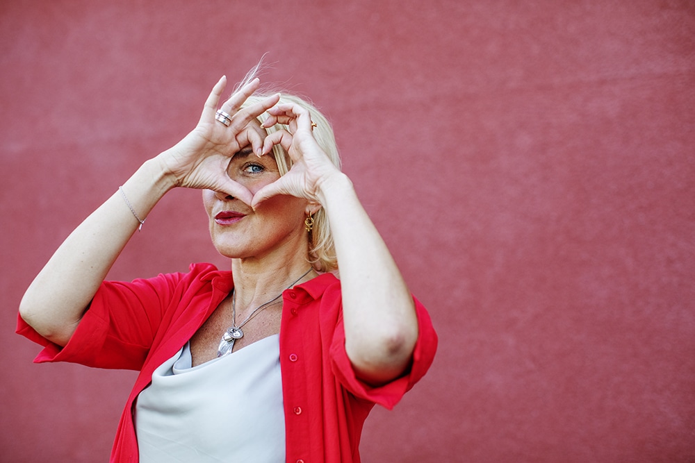 Närbild på Olga Persson som gör hjärttecknet med sina händer, framför ansiktet.