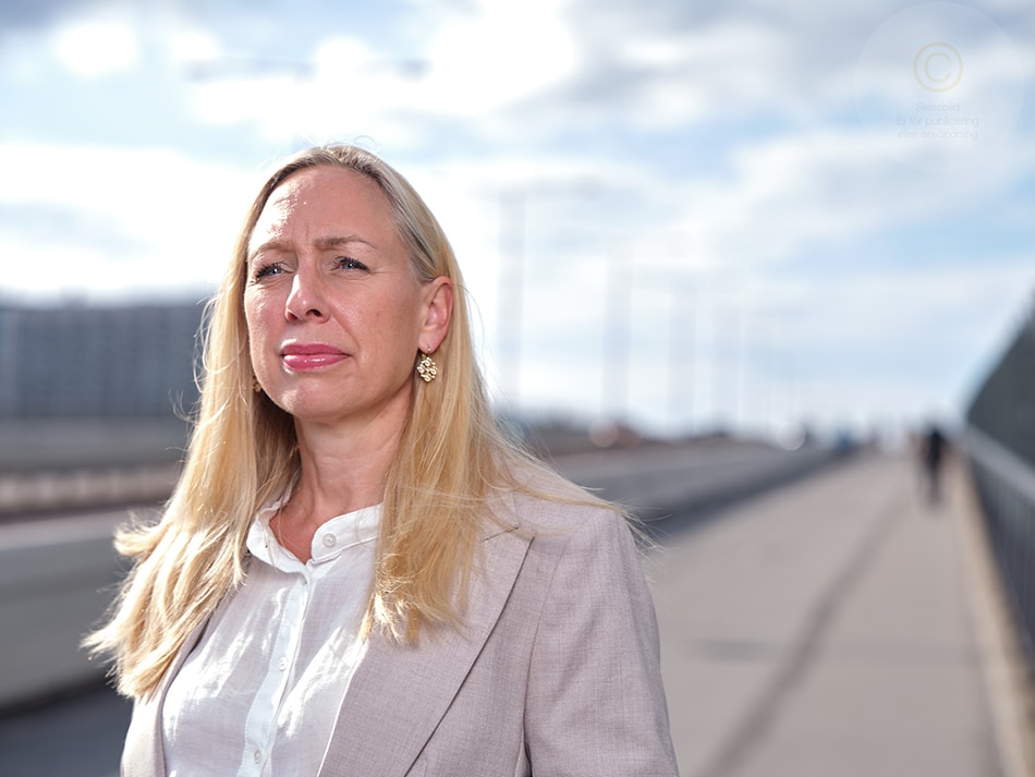 Porträttbild på Anna Sylvén Björnör i halvprofil, ståendes utomhus med en bra bakom sig.