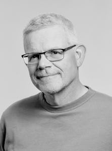 Porträttbild på Ernst Dahlquist i svartvitt, huvud och axlar, ståendes framför en helgrå bakgrund.