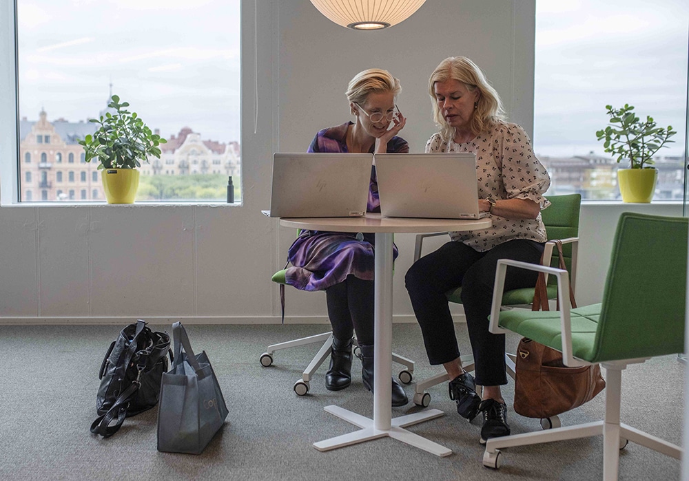 Verksamhetscheferna Elisabeth Svanberg Eriksson och Anna Burston sitter bredvid varandra vid ett skrivbord med varsin laptop framför sig.
