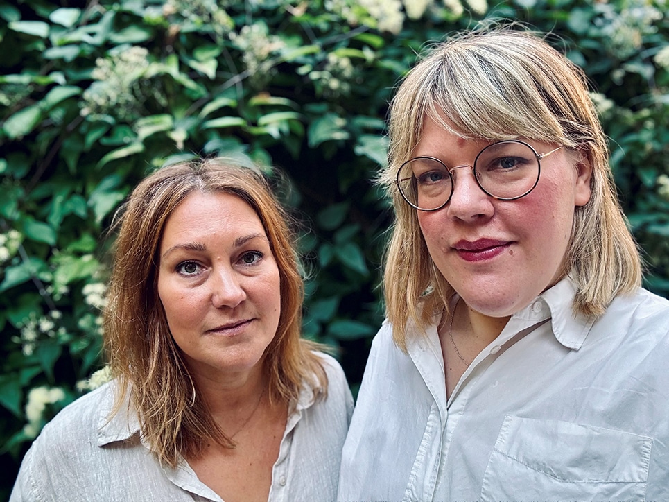 Porträttbild på Stockholms Stads socialtjänstinspektörer Anna Forsström (till vänster) och Johanna Lidman-Strauss, huvud och axlar, ståendes framför ett buskage.
