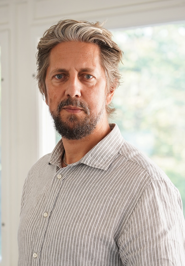 Porträttbild på Emanuel Åhlfeldt, huvud och axlar, ståendes framför ett fönster.