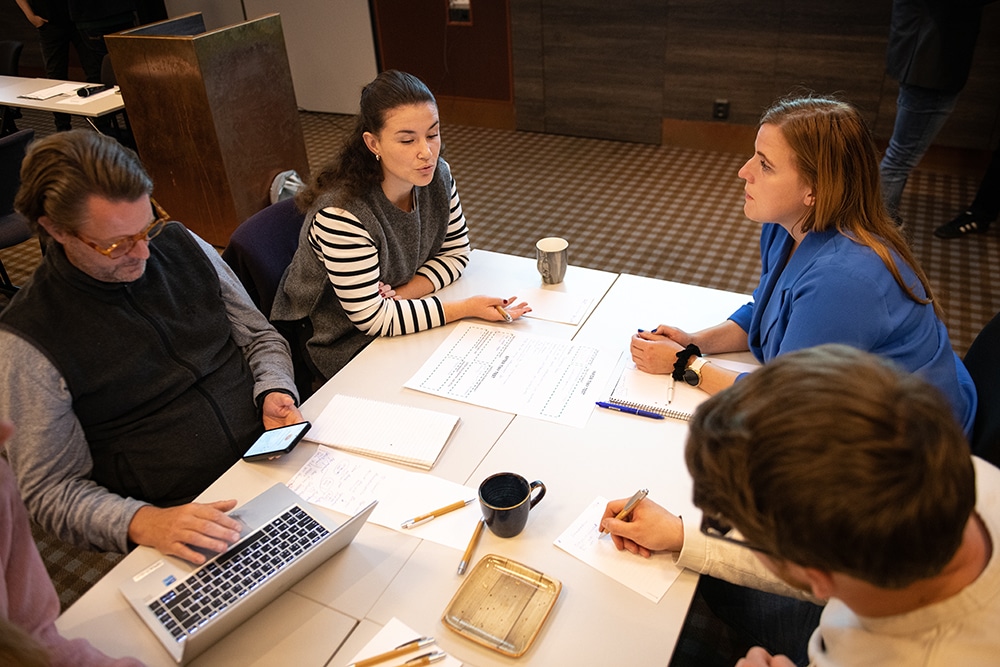 Fyra workshop-deltagare sitter inbegripna i diskussion runt ett bord.