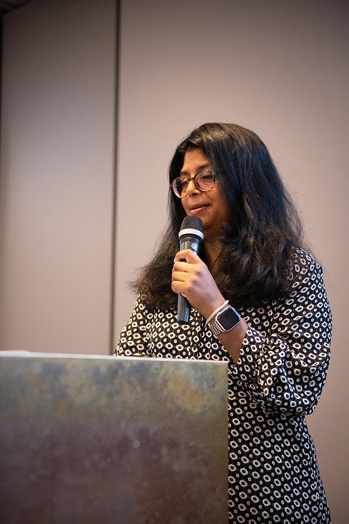 Maria Jörnmyr, socialchef i Grums kommun, står vid ett podium och pratar med en mikrofon i handen.