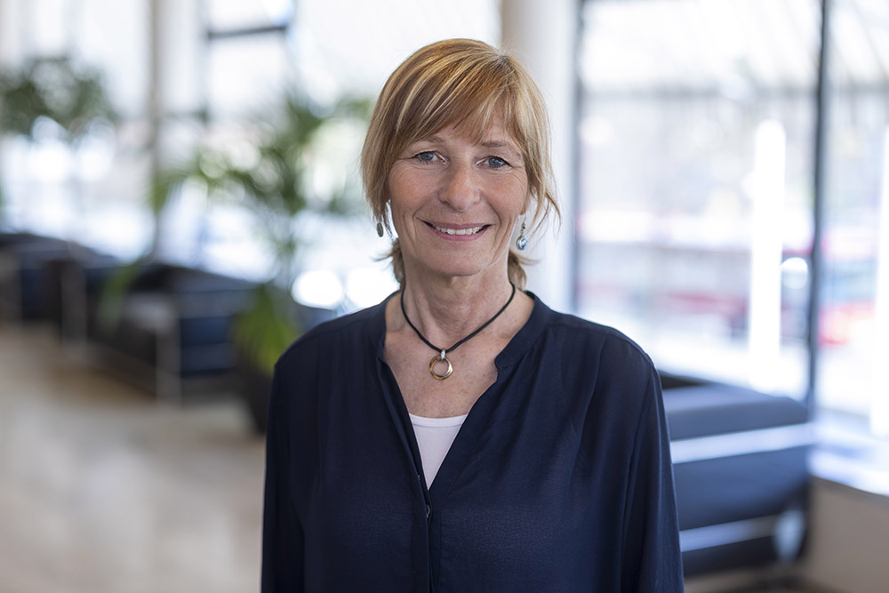 Annika Rådström syns i halvprofil, tittandes rakt mot kameran, i bakgrunden en blurrad lounge.