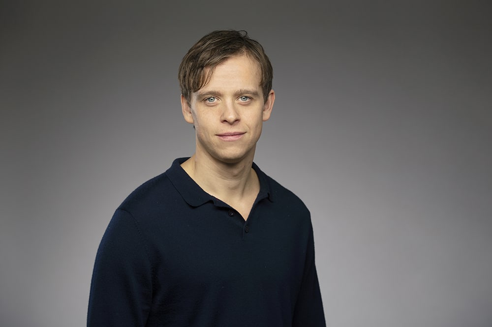 David Pålsson, forskare vid Stockholms universitet, i halvprofil framför en grå bakgrund.