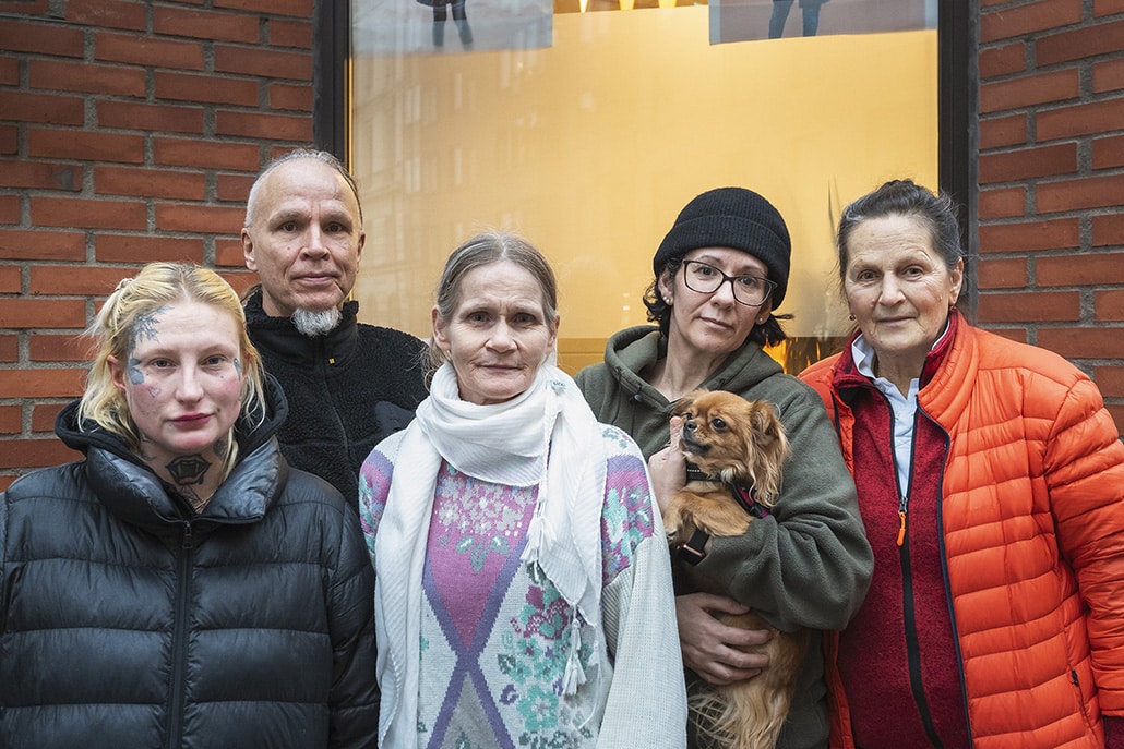 Fem deltagare i Socialpolitiks skrivarcirkel porträtteras i halvprofil, ståendes framför en tegelbyggnad.