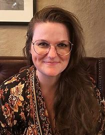 Forskaren Lisa Spang i halvprofil som ser rakt mot kameran, sittandes i vad som ser ut att vara en träsoffa.