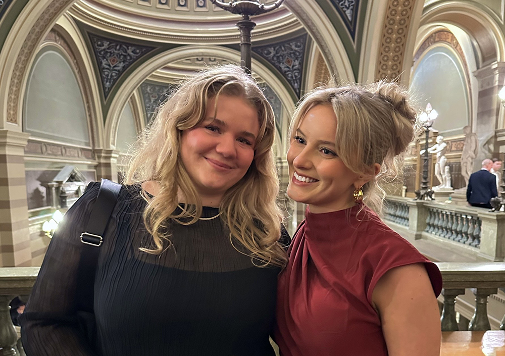 Maya Elder (till vänster) och Kajsa Johansson ståendes bredvid varandra, finklädda i vad som ser ut att vara en kupolbyggnad.