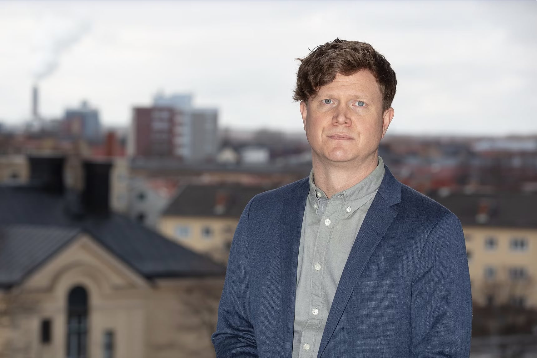 Patrik Jonsson, socialchef i Örebro, syns i halvbild stående framför en suddig stadssiluett.