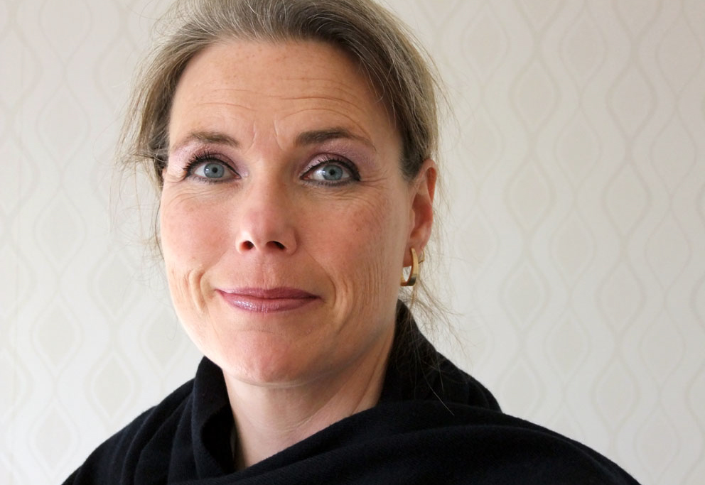 Porträtt av Cecilia Melder, huvud och axlar, framför en ljusbeige bakgrund.
