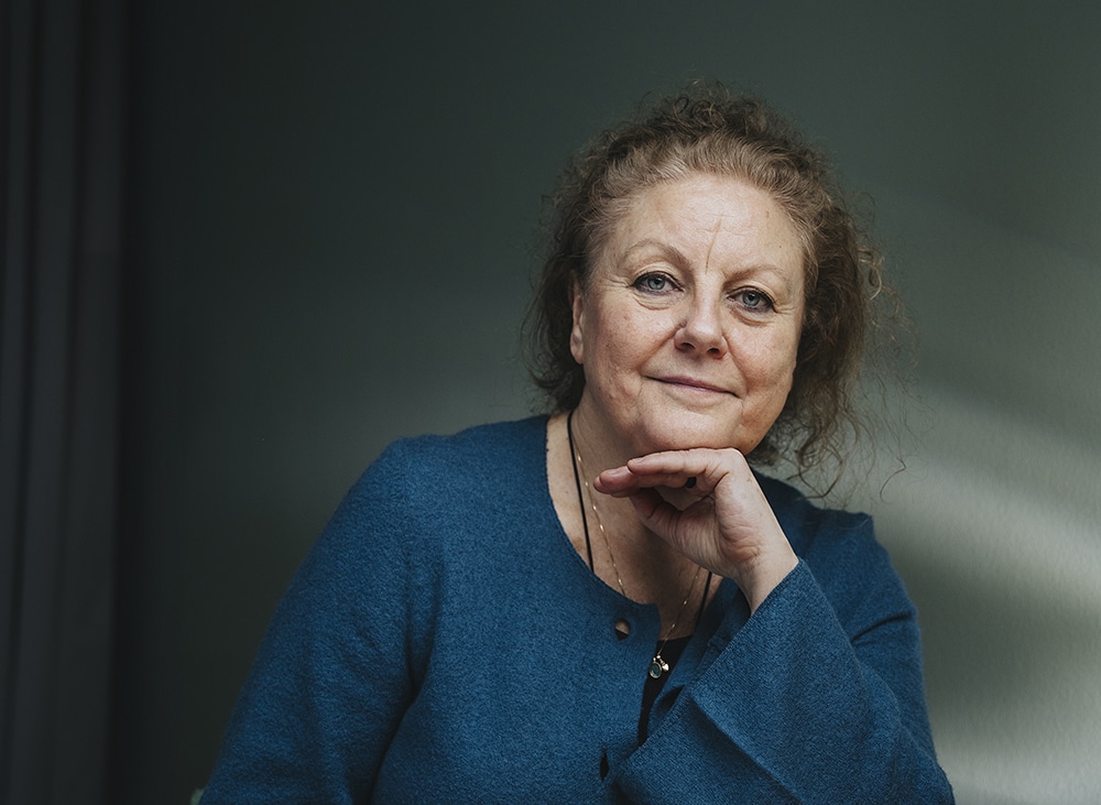 Porträtt av psykoterapeuten Christina Lloyd, halvbild med ena handen under hakan, framför en mörkgrå bakgrund.