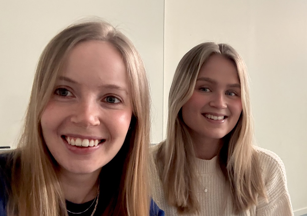 Socionomstudenterna Bianca Dartland och Julia Zakrisson sitter bredvid varandra i ett vitt och kalt rum.