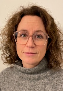 Porträtt av Kristina Kolterud, huvud och axlar, ståendes framför en ljusbrun vägg.