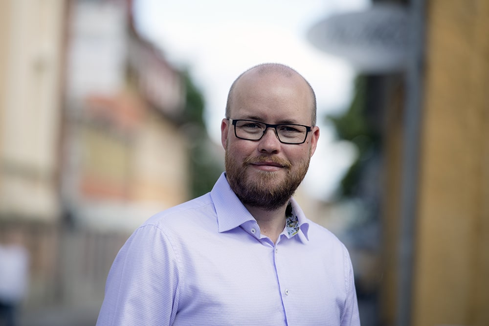 Magnus Nordahl står i halvprofil utomhus framför en suddig bakgrund.