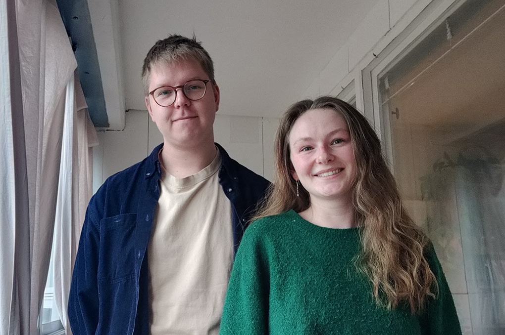 Socionomstudenterna Max Palmgren och Michelle Nilsson i halvprofil, ståendes i ett tillsynes tomt och vitmålat rum.
