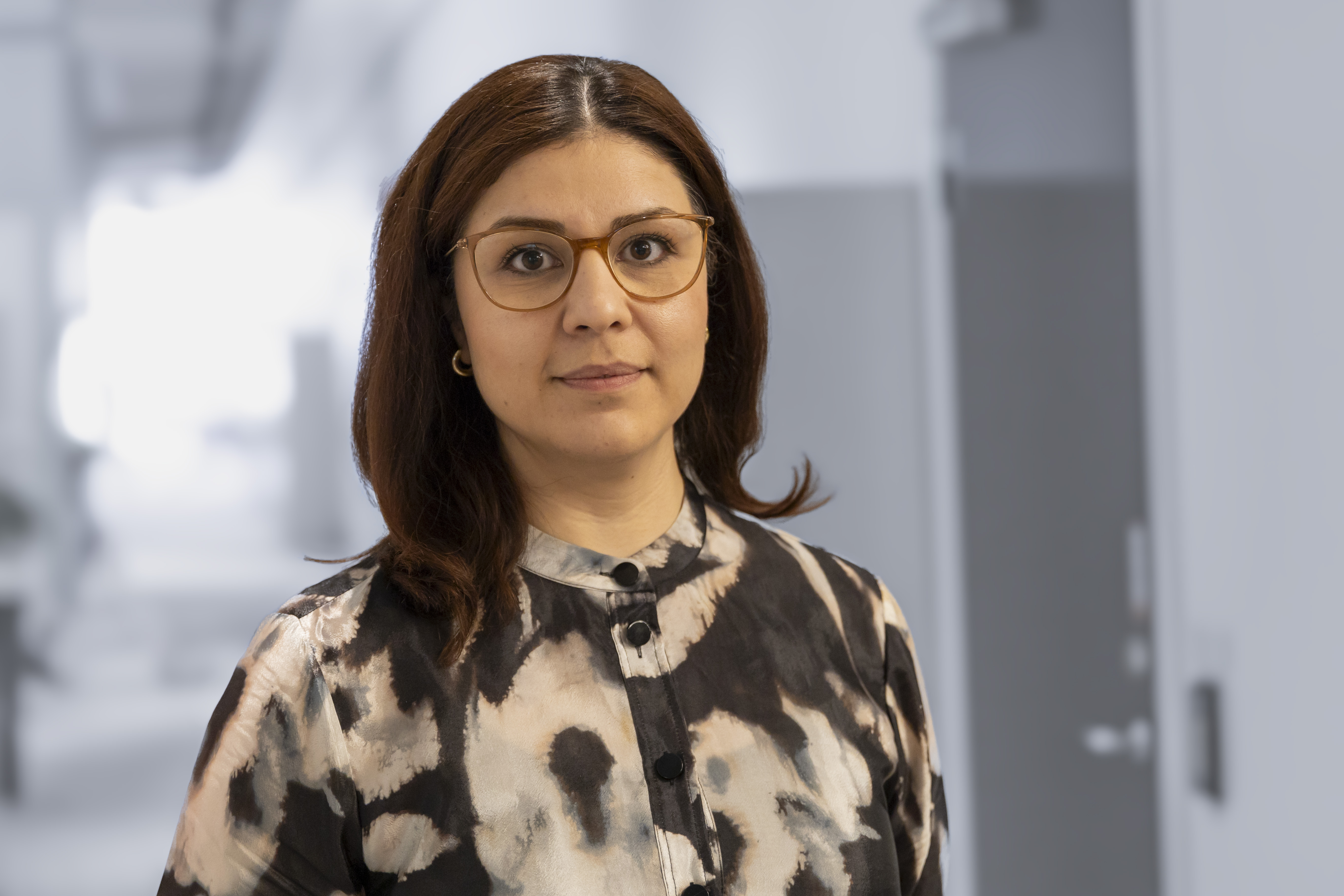 Porträtt av Reza Baar i halvprofil, ståendes i vad som ser ut att vara ett öppet kontorslandskap.