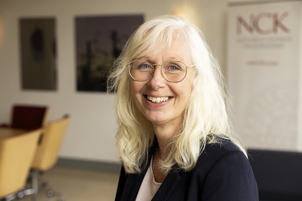Porträtt av Anna Häger i halvprofil, ståendes i ett mötesrum.