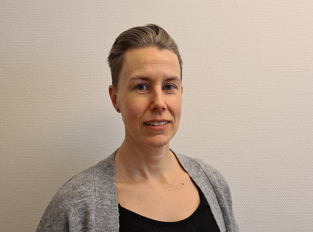 Porträtt av Christin Weikel Vickman i halvprofil, ståendes framför en ljusbeige bakgrund.