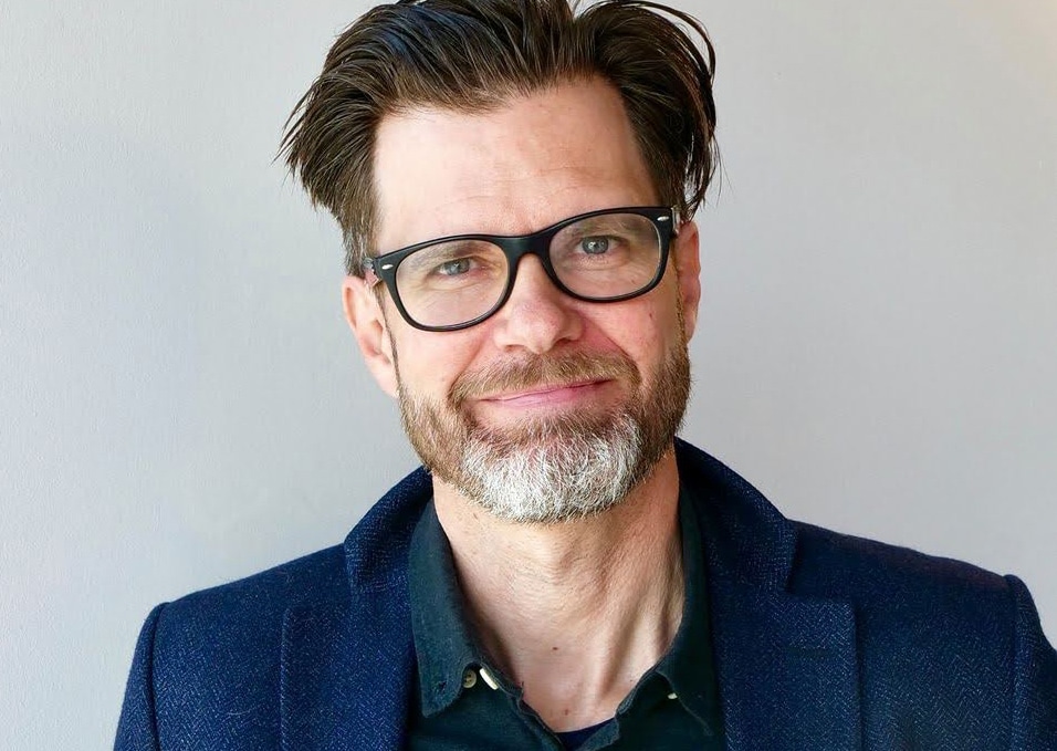 Porträtt av Magnus Svensson, huvud och axlar, ståendes framför en ljusgrå bakgrund.