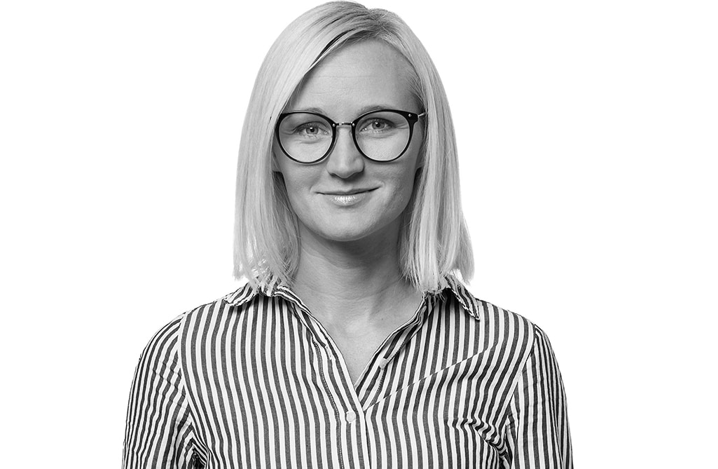 Sandra Boström syns i halvprofil i svartvitt, ståendes framför en vit bakgrund.