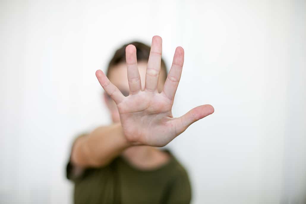En person sträcker fram sin hand mot kameran och signalerar "Stopp". Ansikte och huvud syns inte utan är täckt av handen.