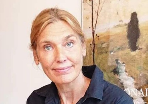 Porträtt av Åsa Flood Johansson i blond hår och en mörkblå skjorta tittandes in i kameran.