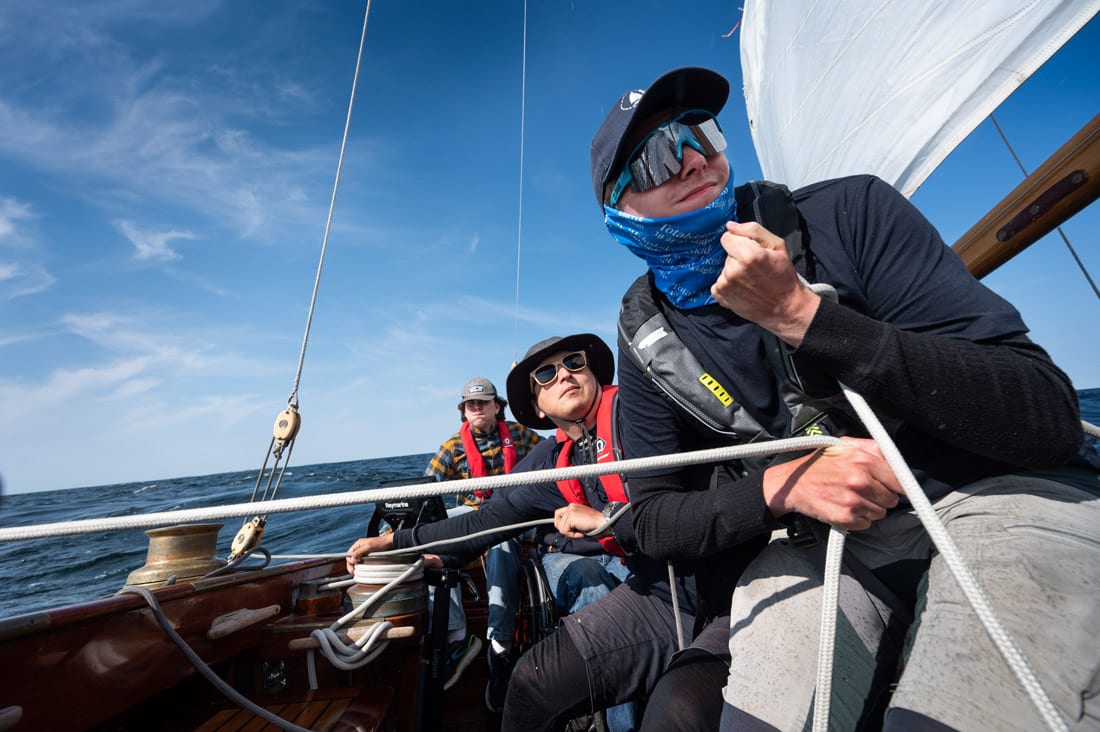 Tre personer i en segelbåt.