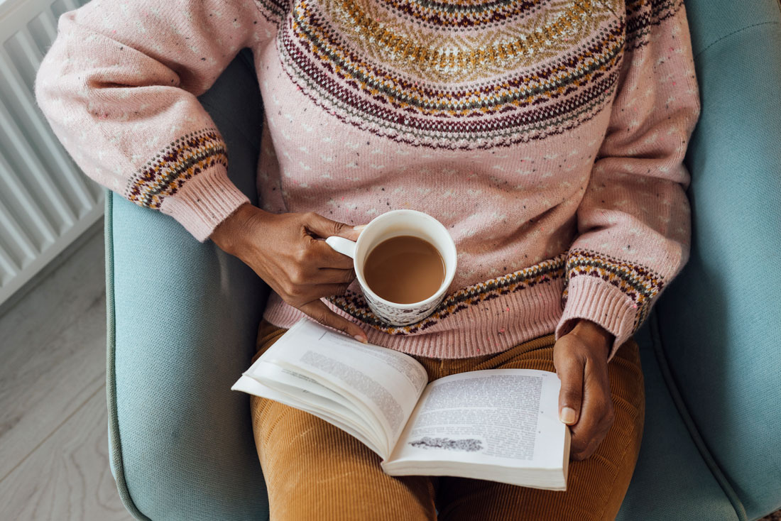 En person som läser en bok och dricker kaffe.
