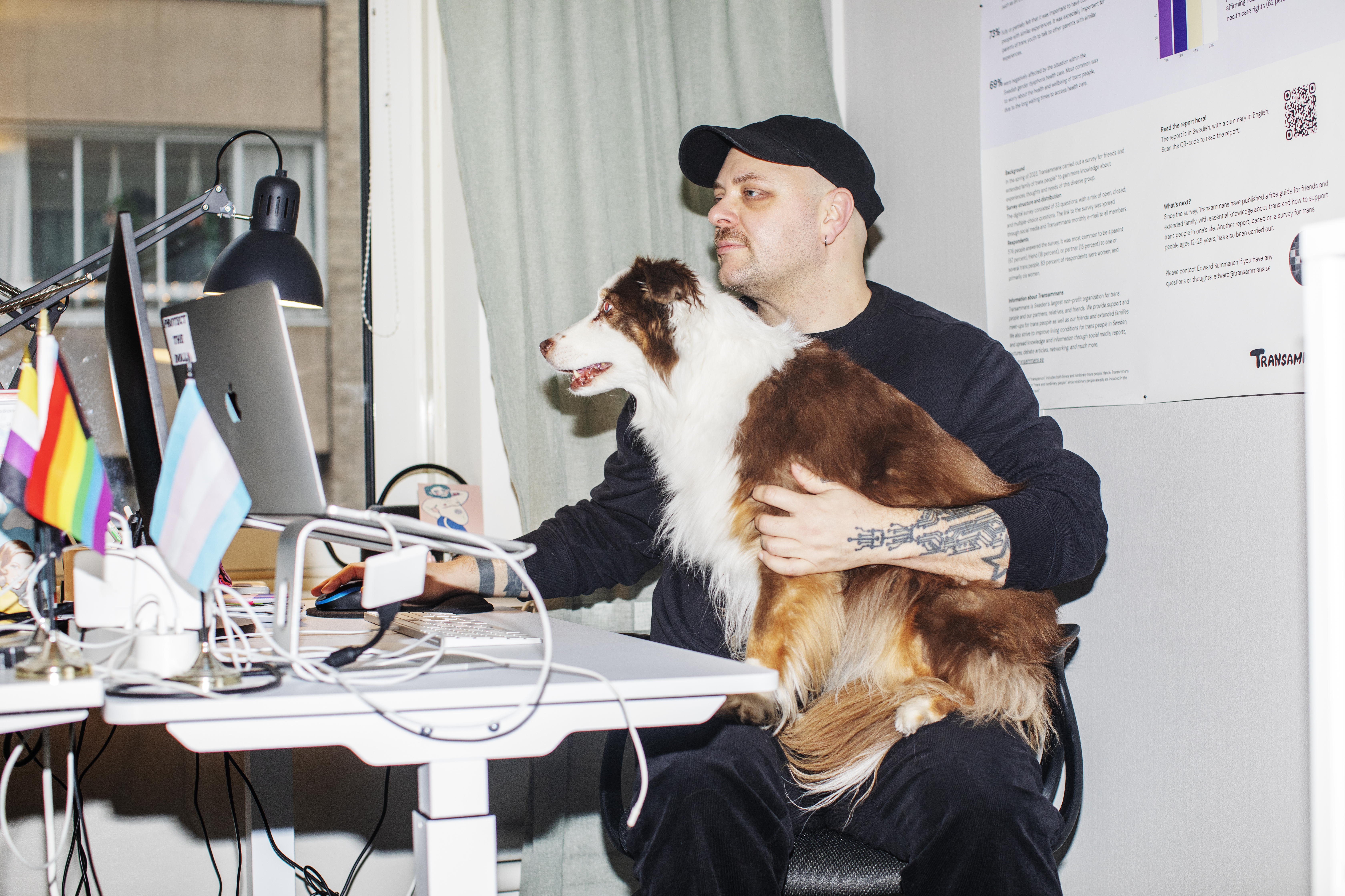 Edward Summanen med hunden Dolly i knät framför skrivbordet.