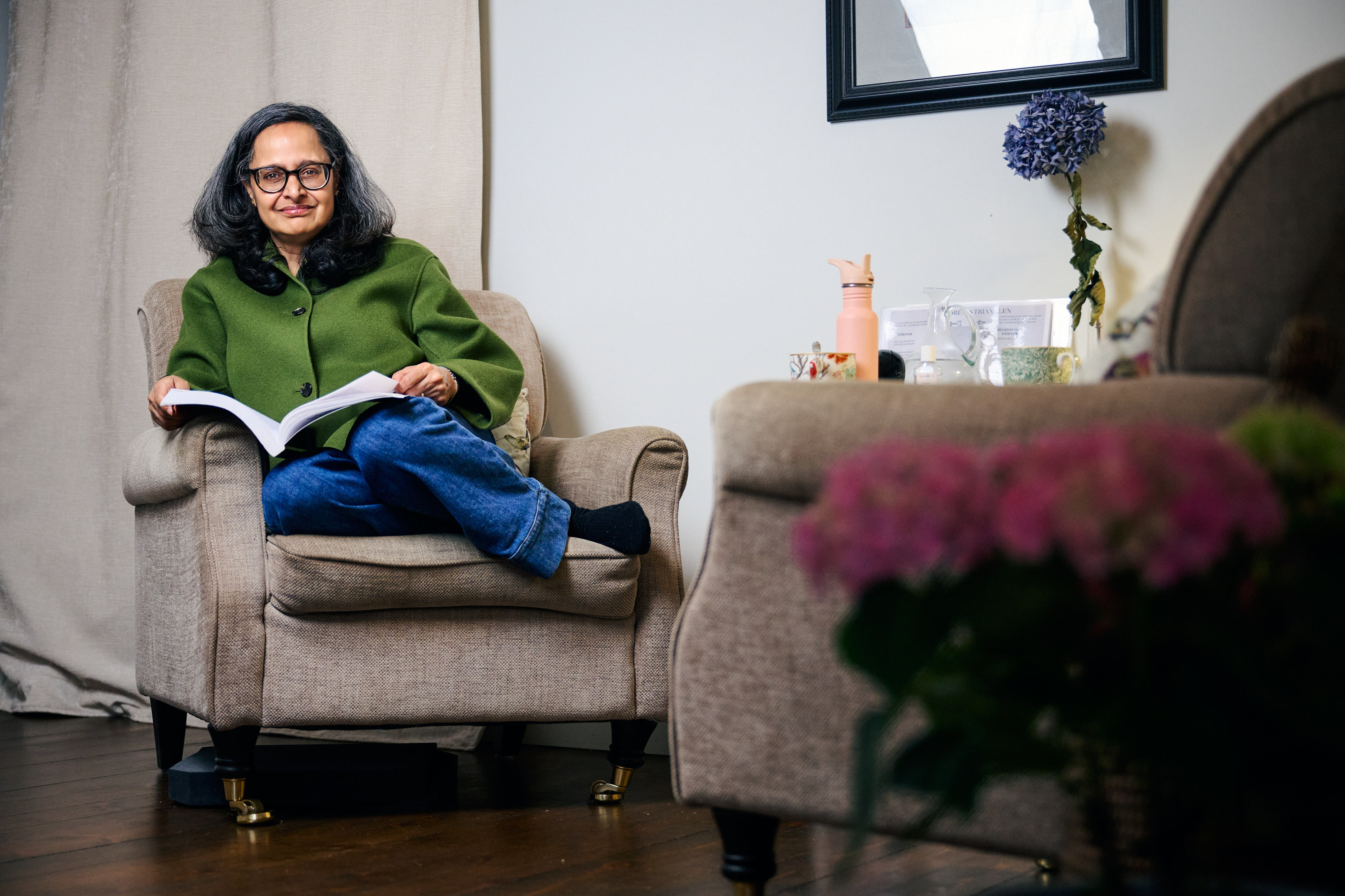 Anna Amazeen sittande i en fåtölj med en bok i handen.