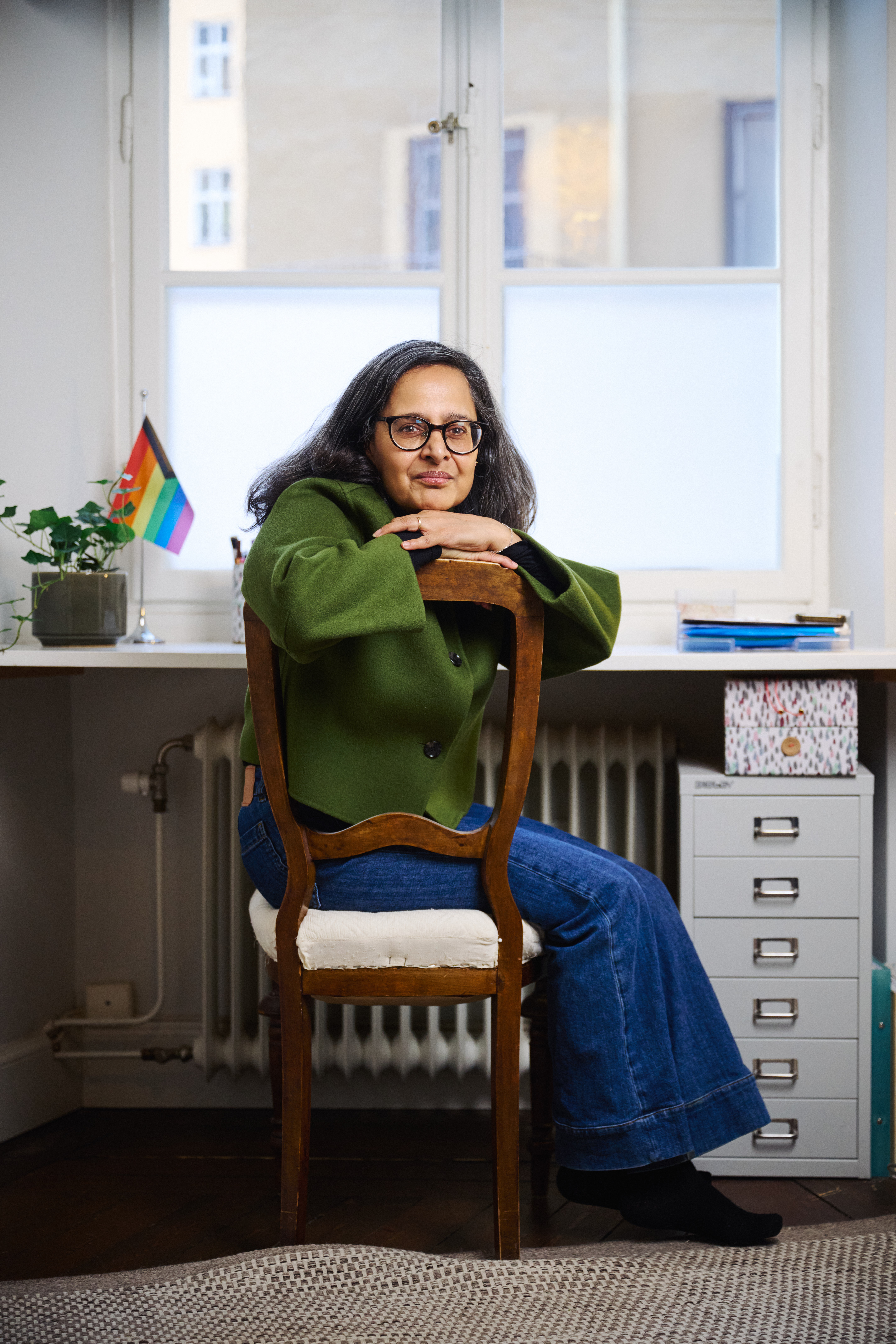 Porträtt på Anna Amazeen vid hennes skrivbord med ren liten egnbågsflagga synlig bakom henne.