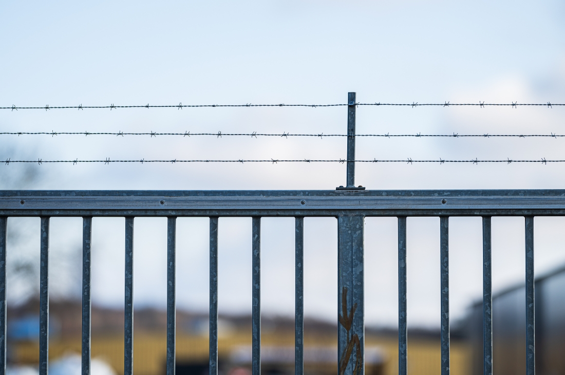 En grind och taggtråd kring ett häkte.