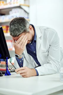Manlig farmaceut ser stressad ut på arbetsplatsen,