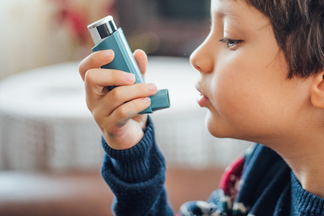 Ett barn använder en inhalator medan hen sitter inomhus.
