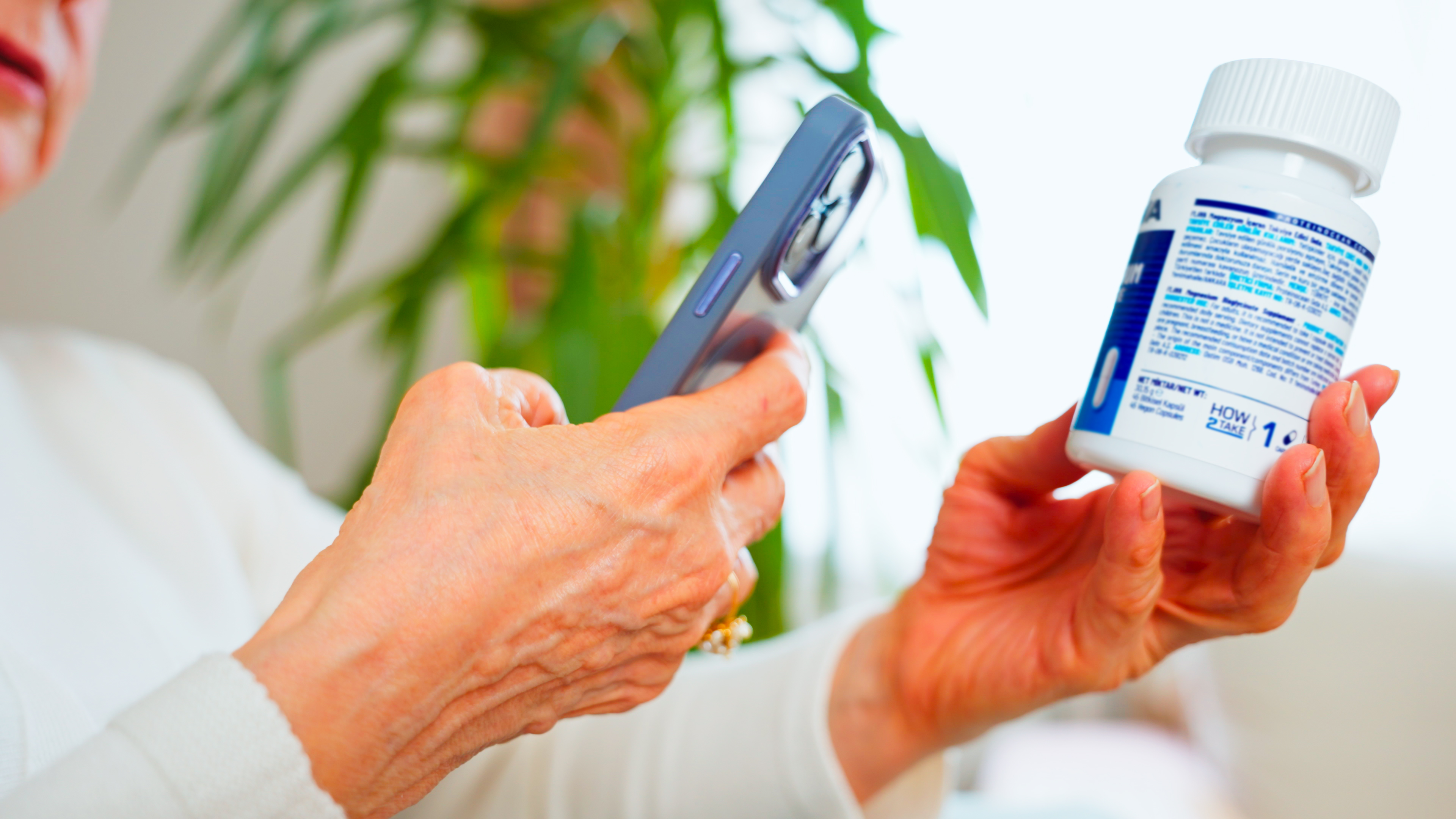 En person håller en mobiltelefon i ena handen och en receptbelagd medicinflaska i den andra och tycks skanna etiketten.