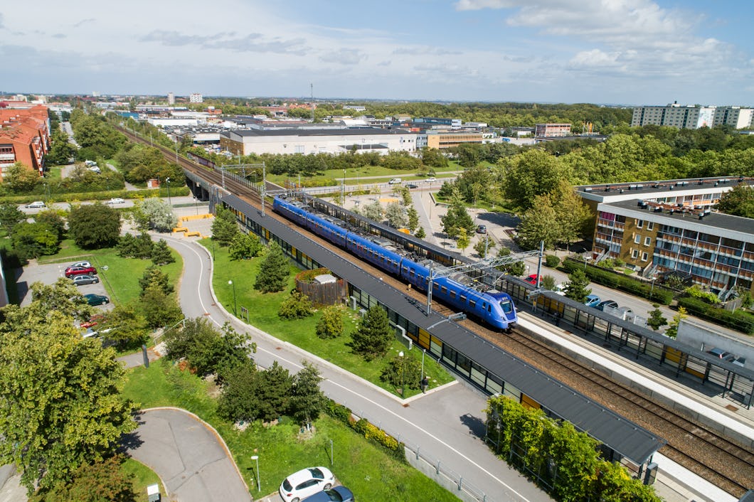 En flygfoto av ett blått tåg som reser genom en stad.