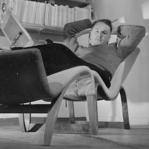 En man som sitter i en stol och läser en bok.