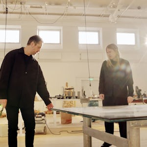 Två personer står runt ett bord i en konststudio.