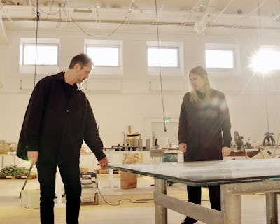 Två personer står runt ett bord i en konststudio.