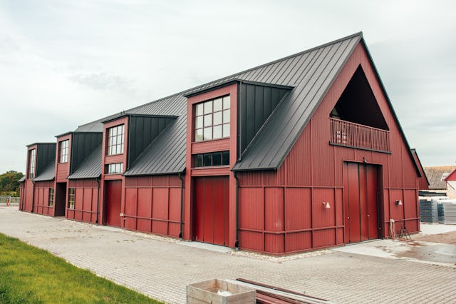 En röd ladugård med svart tak.